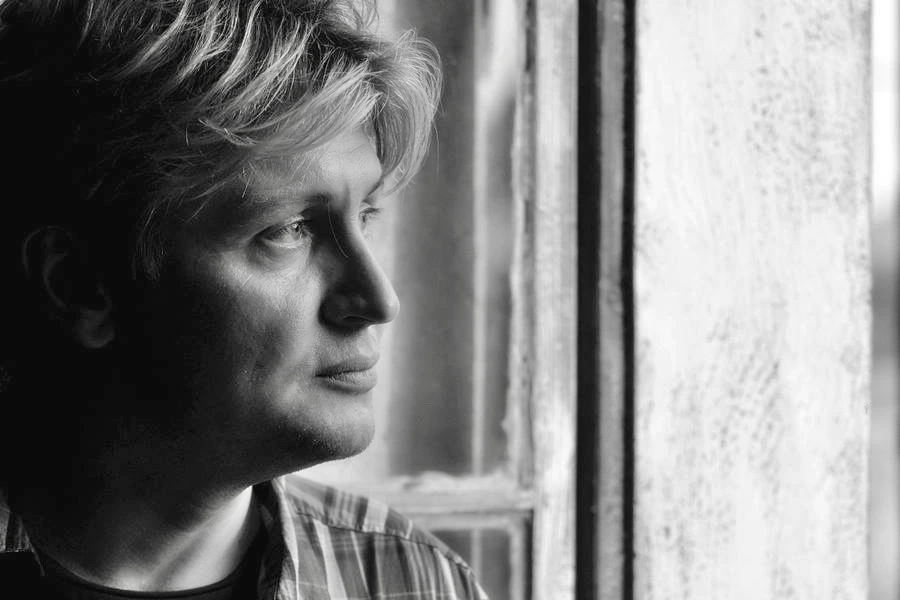 Black-and-white portrait of Xavér Varnus looking out a window