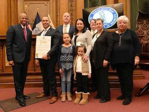 Phil Vetrano at an event with family and officials, standing in a wood-paneled room during a recognition ceremony.