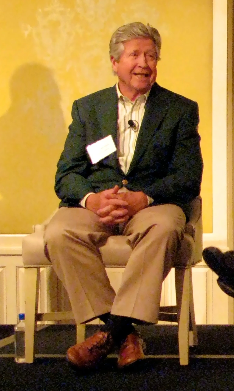 Don Valentine seated at an event, wearing a blazer and khaki pants