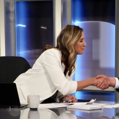 Vassy Kapelos in a studio setting shaking hands at a desk