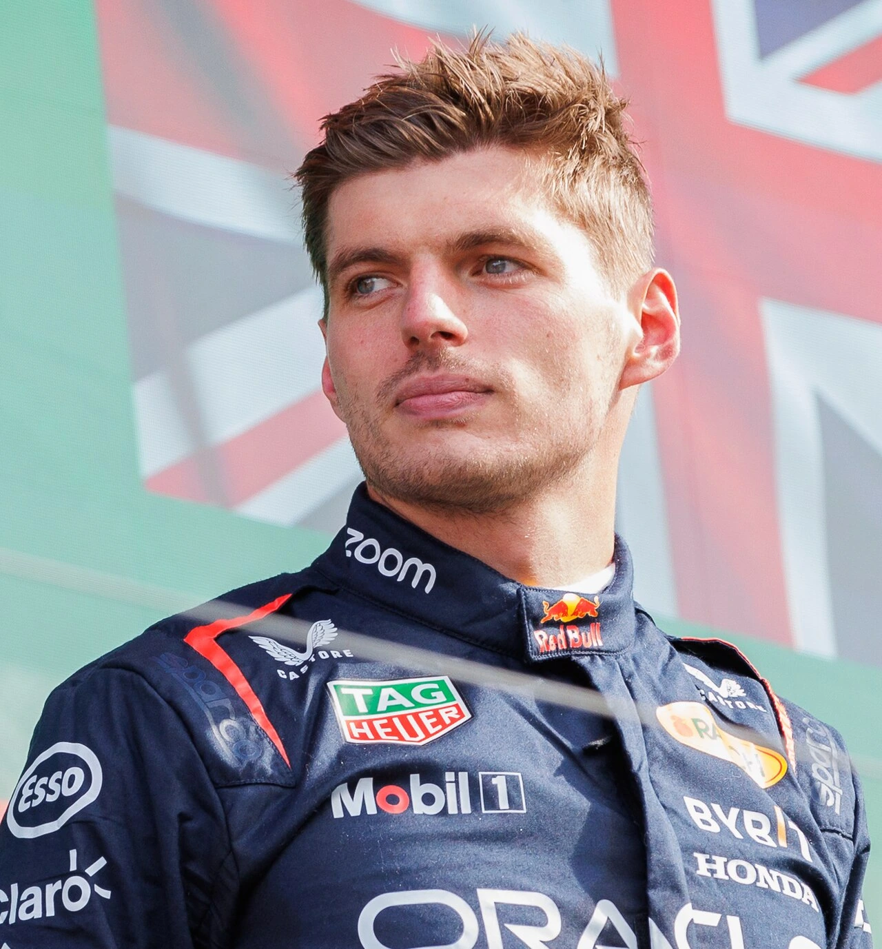 Max Verstappen in Red Bull racing suit at a Formula 1 event, looking off to the side.