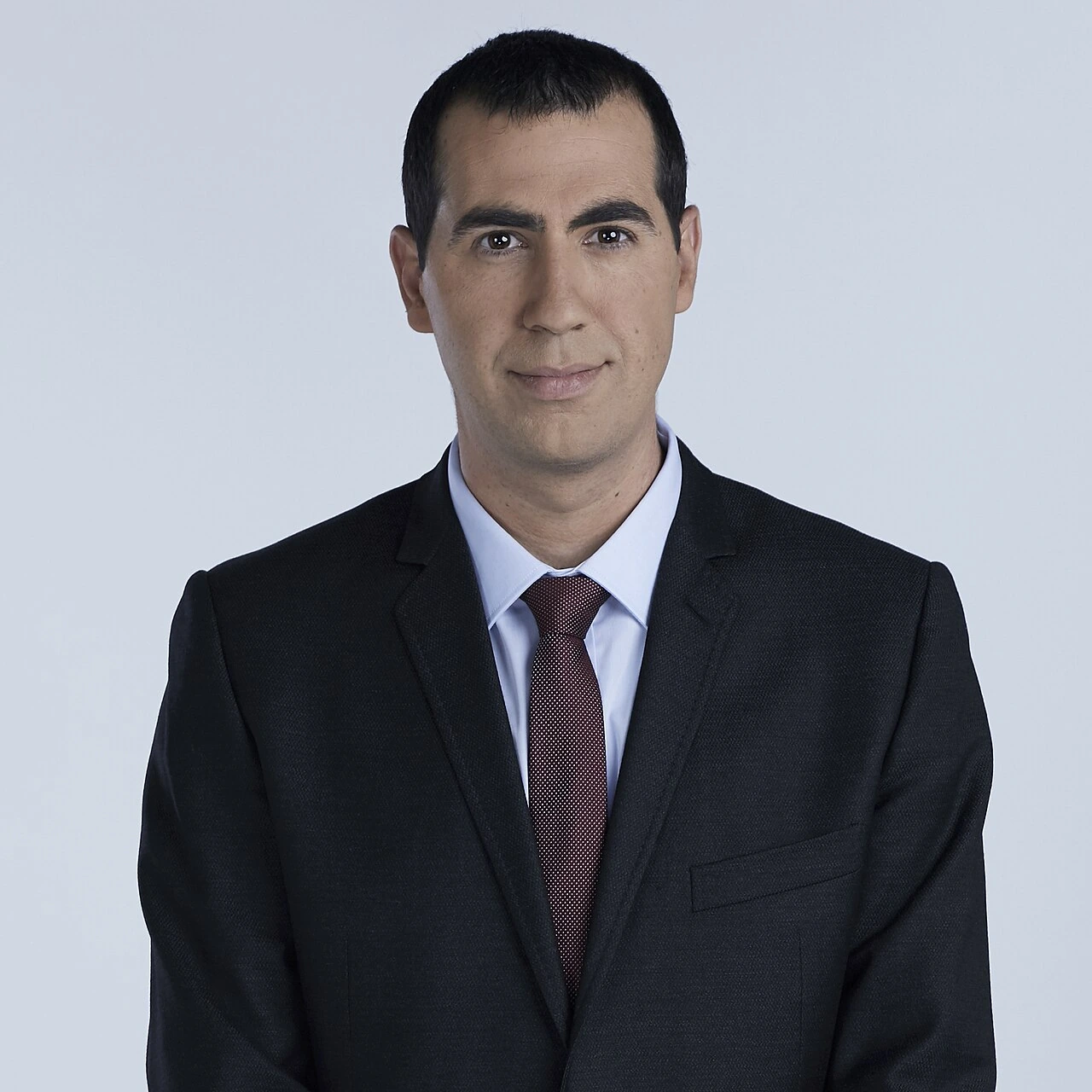 Portrait of Guy Yovan in a dark suit and tie against a plain light background