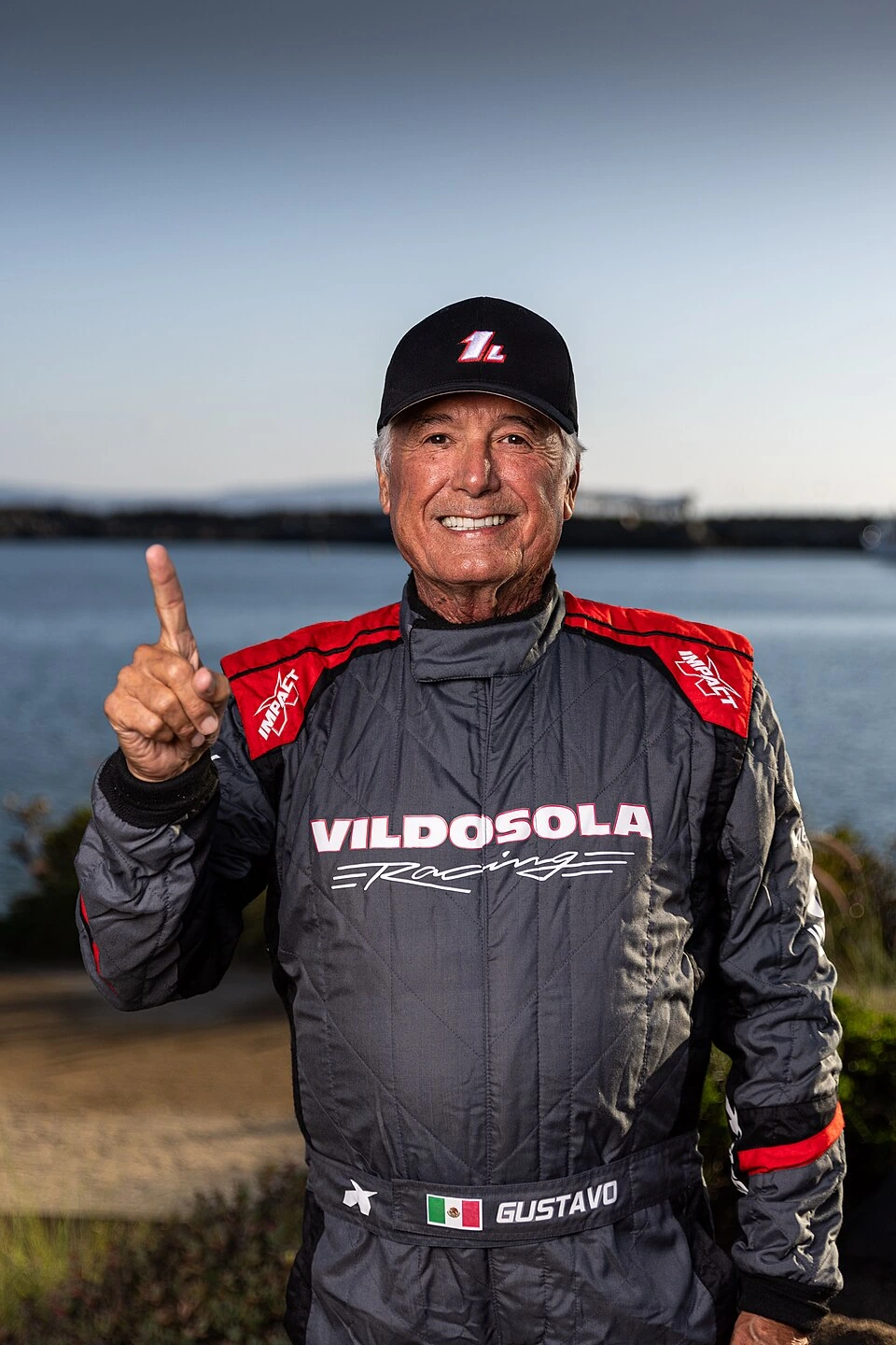 Gustavo Vildosola in a racing suit and cap standing outdoors by the water